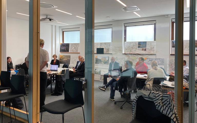 Työryhmä ikkunan takana kokoushuoneessa.