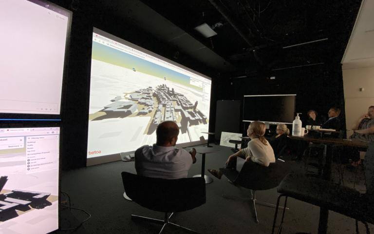 Ihmiset istuvat valkokankaan edessä katsomassa kuvia.