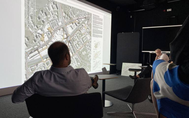 Ihmiset istuvat valkokankaan edessä katsomassa kilpailun kuvia.