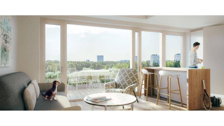 Sisäkuva asunnon olohuoneesta ja ruokailutilasta sekä vehreästä kaupunki maisemasta, joka näkyy ikkunasta.